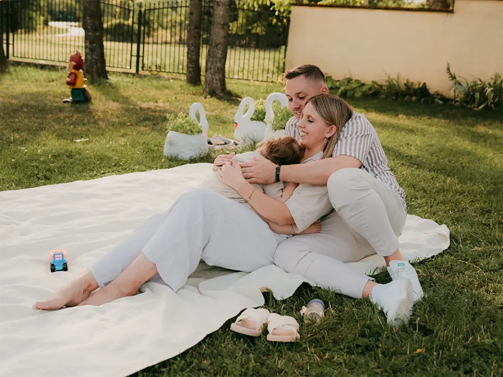 Romantikus pár fotója pléden ülve, pici babával, őszi környezetben.
