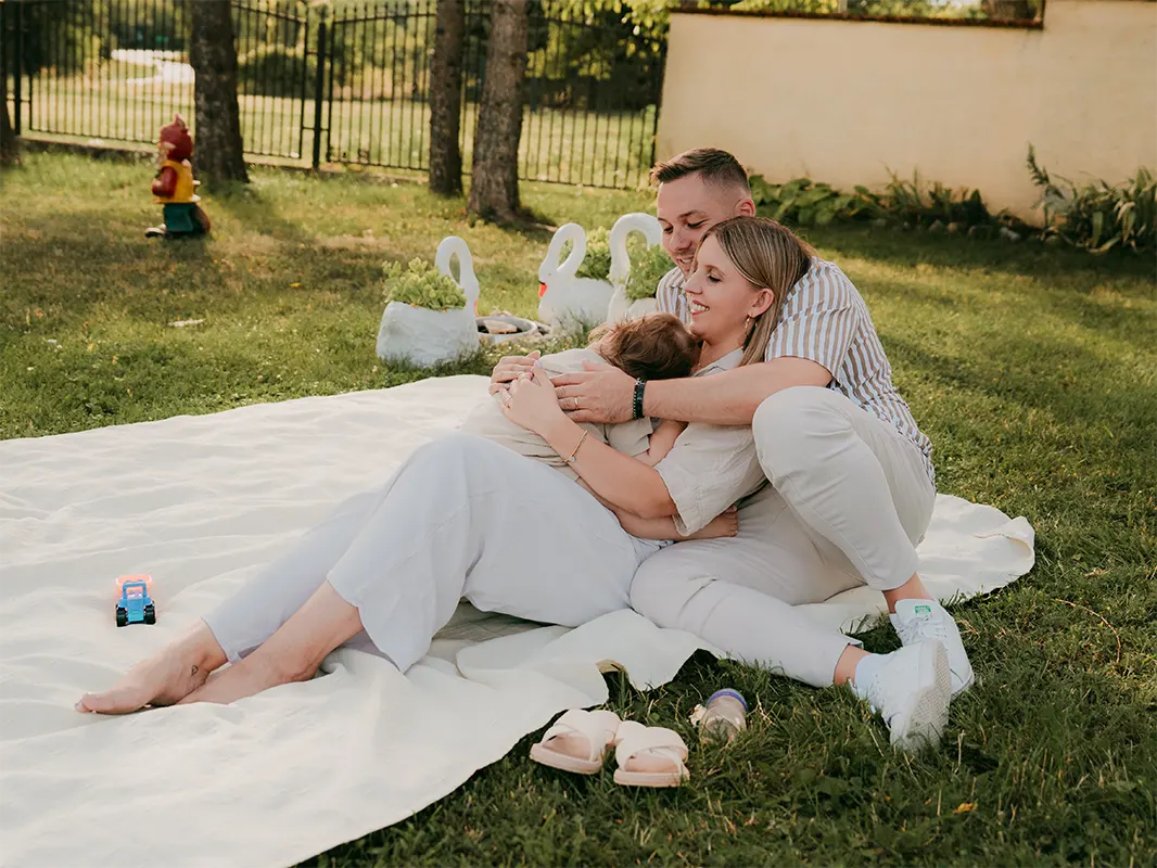 Romantikus pár fotója pléden ülve, pici babával, őszi környezetben.